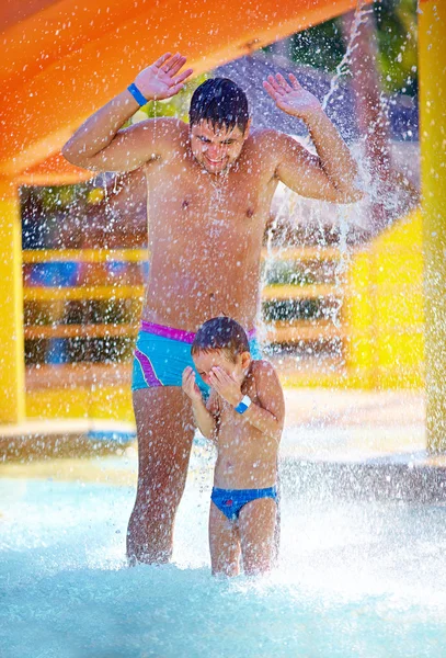 Happy excited family under water stream in water park