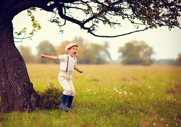 Cute excited boy having fun on spring field, countryside