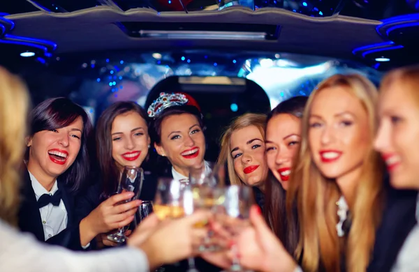 Group of happy elegant women clinking glasses in limousine, hen party