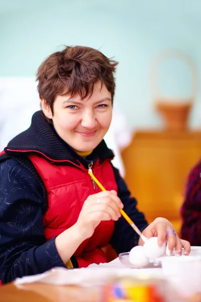 Young adult woman with disability engaged in craftsmanship in rehabilitation center