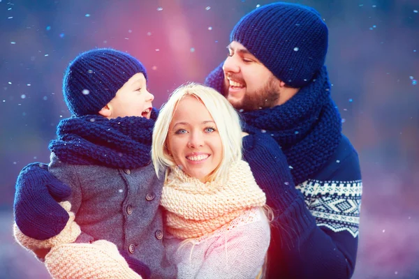 Portrait of happy family having fun under winter snow, holiday season