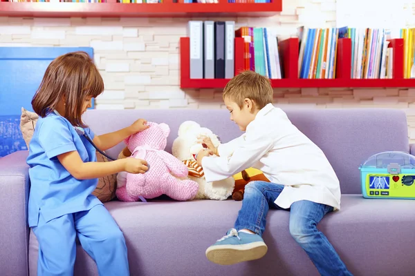 Cute kids playing doctors with toys in office