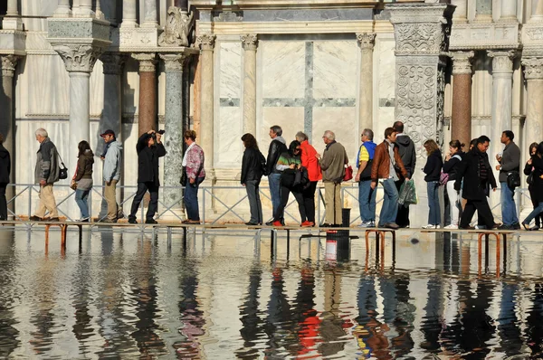 Venice sinking beneath the sea, tourists walk on duck boards