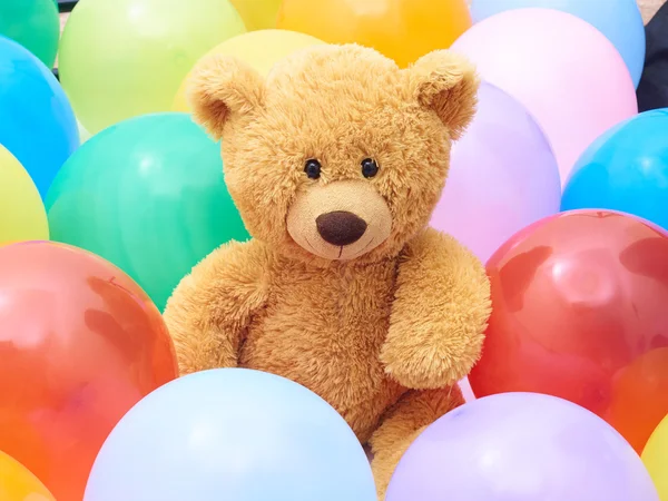 Teddy bear  in colourful balloons closeup.
