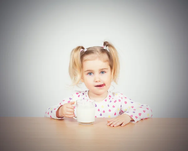 Happy little girl with a glass of milk.