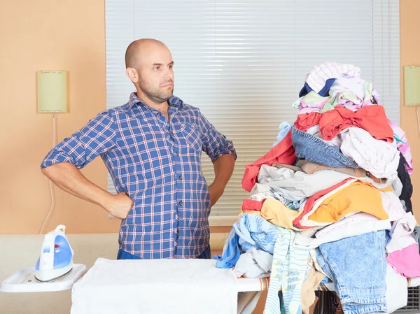 Caucasian man ironed clothes in the room near the window.