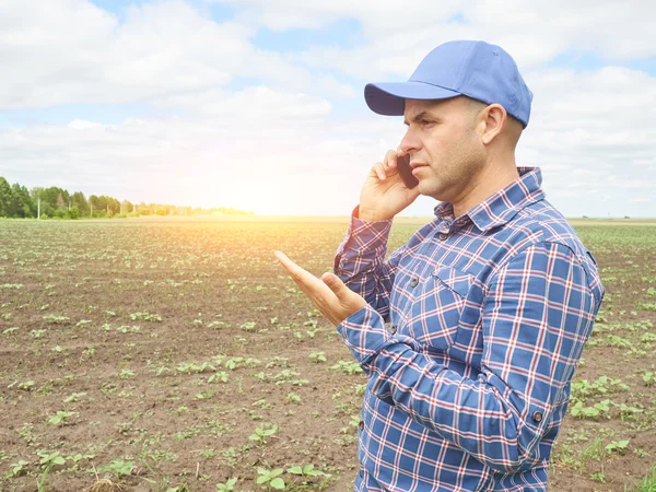 Farmer in a plaid shirt controlled his field.Talking on phone.