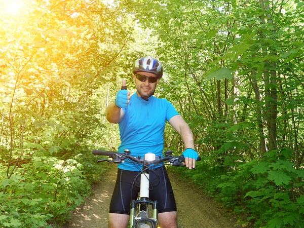 Happy man riding a mountain bike in the green woods.