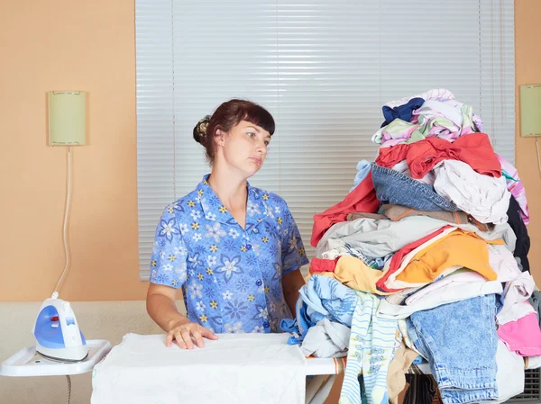 Young Caucasian woman ironed clothes in the room near  window.