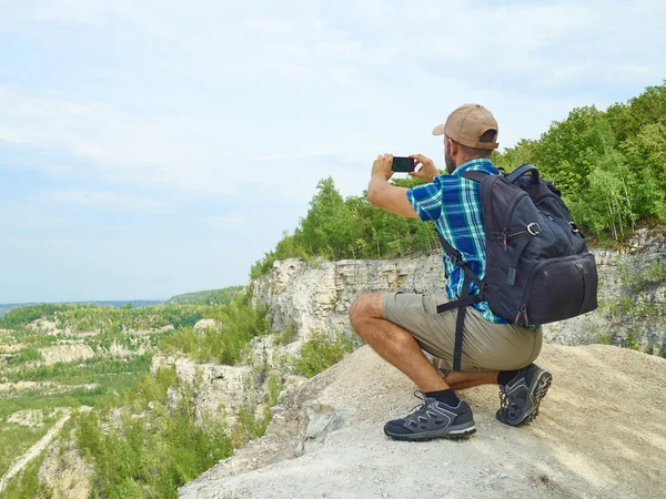 Man tourist is using a smartphone while sitting on the edge of a