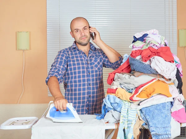 Caucasian man ironed clothes and talking on the phone.