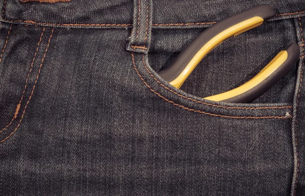 Pliers with yellow handle in a pocket of jeans.  background.