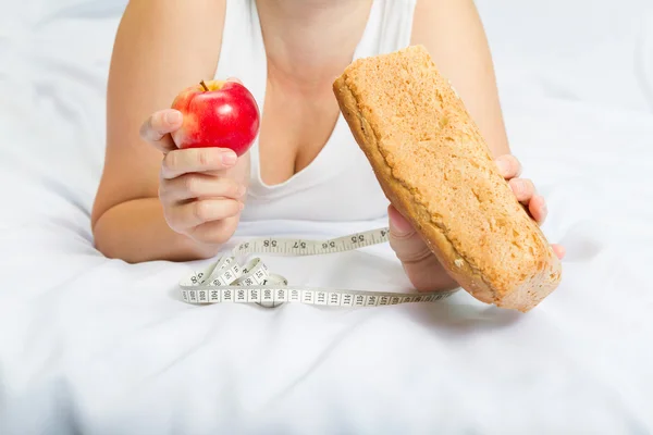 Girl  holding an Apple and bread .