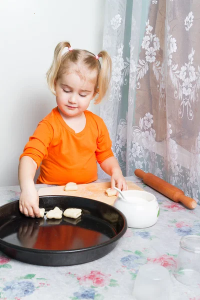 Little girl making dough in the kitchen.