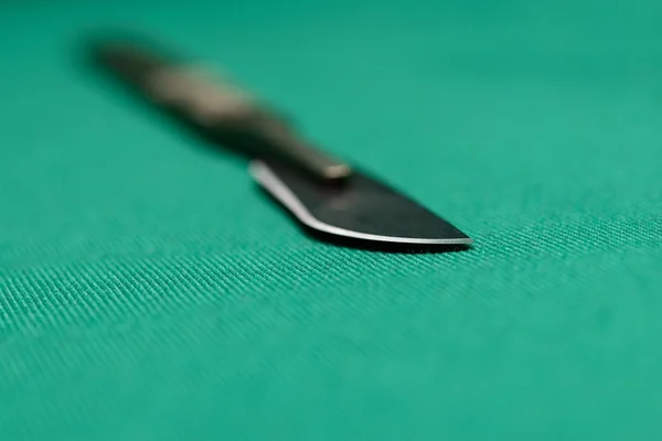 Scalpel on green surgical drapes with shallow depth of focus