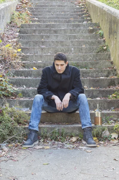 Depressed man on concrete stairways with alcohol drink