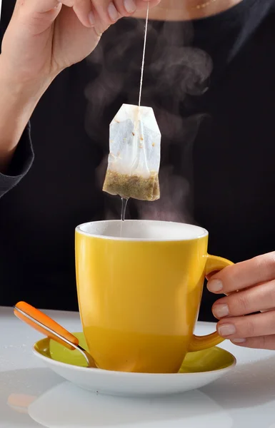 Woman soaking tea bag in  cup