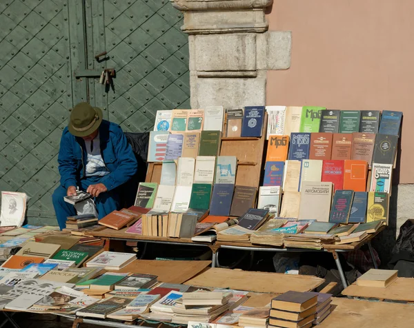 LVIV, UKRAINE - OCTOBER 4, 2014: Book flea market near the monument of Ivan Fyodorov. Old man looking through second hand book near other books on 4 October 2014, Lviv, Ukraine.