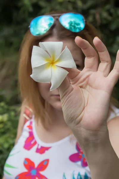 The girl in a color shirt holds in hand a flower