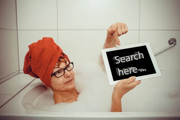Woman in bathtub with tablet computers, space for text