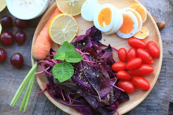 Fresh red spinach salad and cream on wooden table