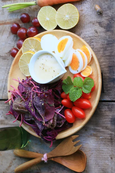 Fresh red spinach salad and cream on wooden table