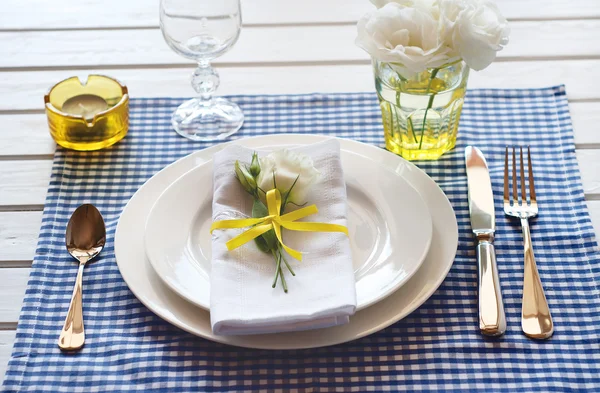 Table setting with blue checkered tablecloth, white napkin