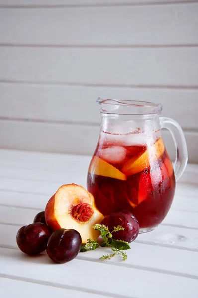 Iced fruit compote with peaches and plums. Cold summer drink.