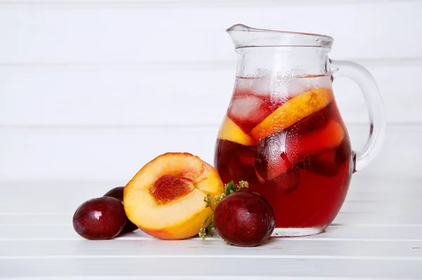 Iced fruit compote with peaches and plums. Cold summer drink.