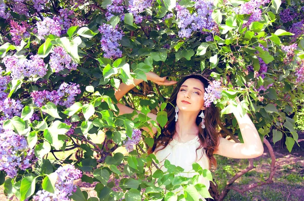 Woman with long brown hair in lilac bushes