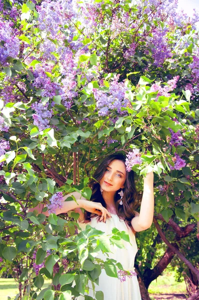 Woman with long brown hair in lilac bushes
