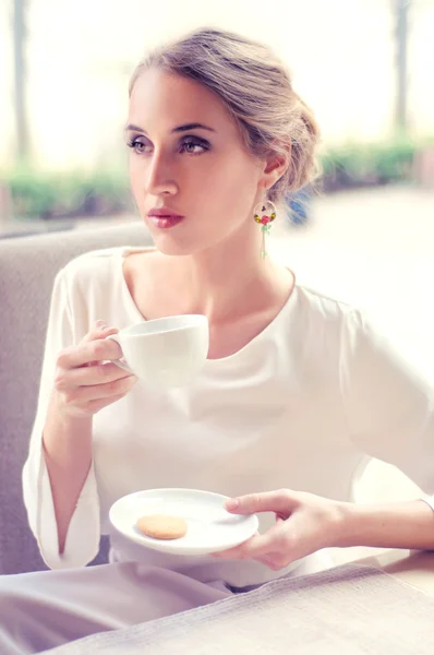 Beautiful elegant blonde sitting in a cafe drinking tea