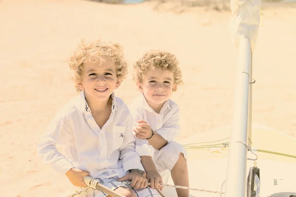 Two blond brothers are having fun on the beach in a sunny day