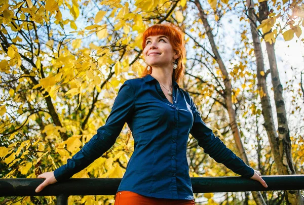 Beautiful woman in autumn park with yellow leaves background. Concept of heat, positive energy, nature enjoy.