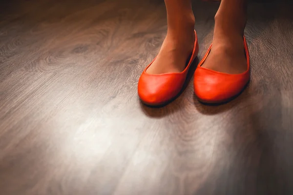 Unusual wedding shoes on the feet of the bride, bright orange, at home