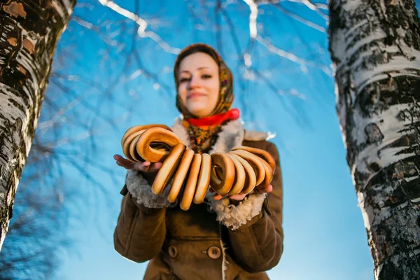 Young beautiful woman clothed in russian winter suite with bagels