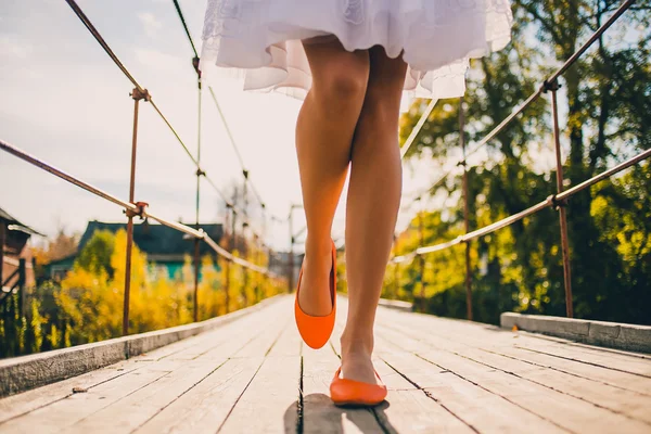 Unusual wedding shoes on the feet of the bride, bright orange, walk in the park