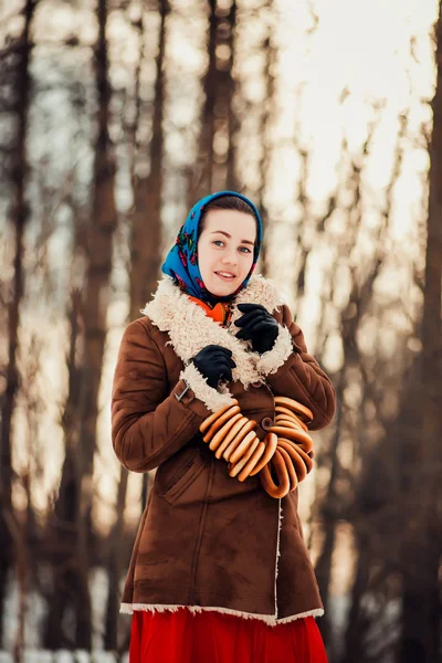 Young  charismatic attractive  woman clothed sheepskin coat and scarf. Girl holding the bagels. Spring time