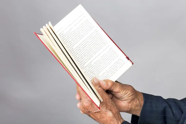 Closeup of old man hands holding an open book