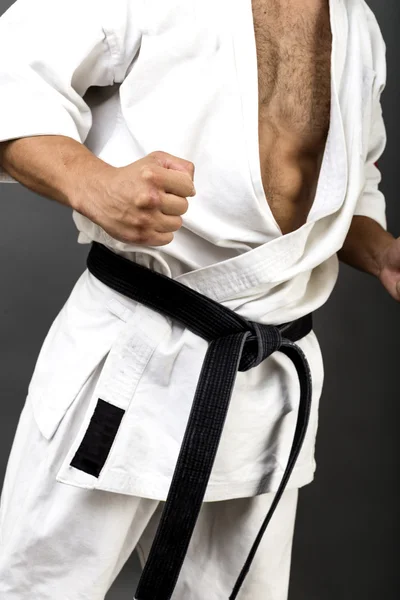 Young man in white kimono and black belt training martial art