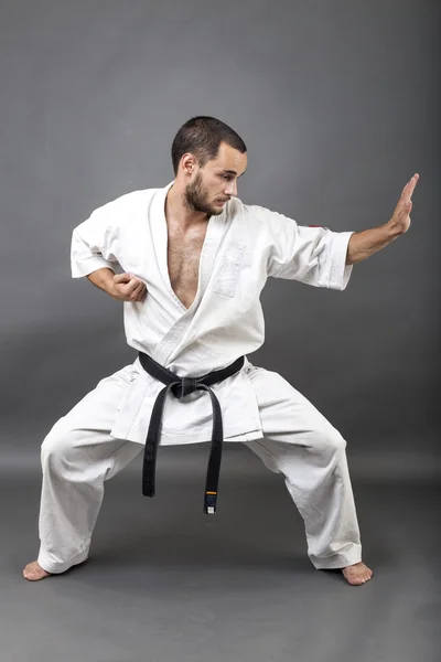 Full length portrait of young man in white kimono and black belt