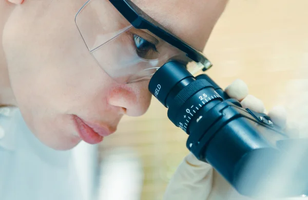 Close up of female scientist looking to microscope in clinical l