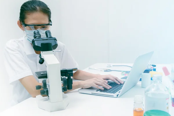 Close up of female scientist looking to microscope in clinical l