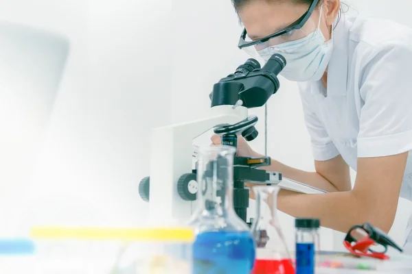 Close up of female scientist looking to microscope in clinical l