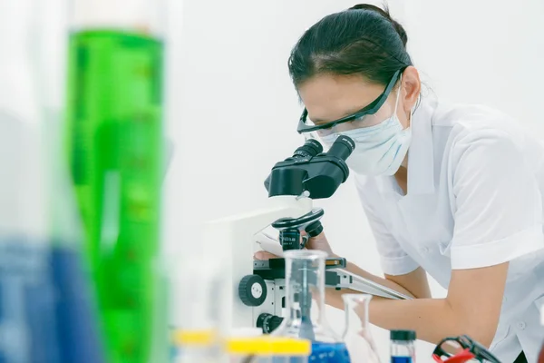 Close up of female scientist looking to microscope in clinical l