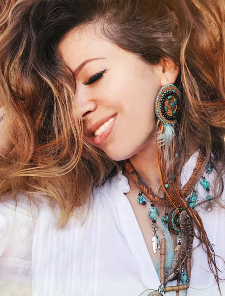 Beauty close up fashion smiling woman portrait with handmade necklace and earrings made with beads, leather and feathers, boho chic style, perfect skin and volume curly hairstyle, outdoor photoBeauty