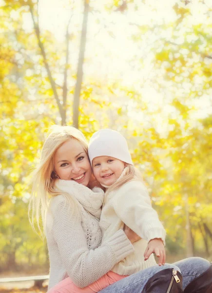 Portrait of a happy family with beautiful blonde mother and little daughter resting in park.