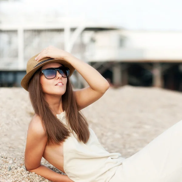 Happy fashion dressed woman in hat rest sitting on a beach.