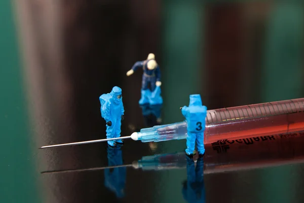 Small people studying syringe. The concept of health