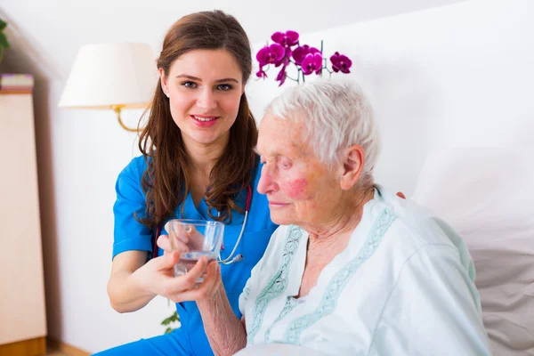 Caring nurse helping sick elderly woman